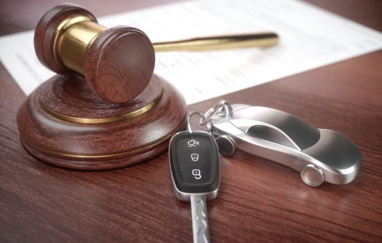 Auction hammer with golden details, a car key next to it and a contract in the background.