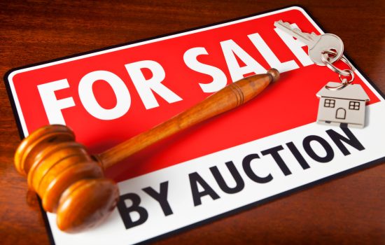 "Home for Sale by Auction. For Sale sign with auctioneeraas gavel and a chrome house key fob, with house key. Copy space."